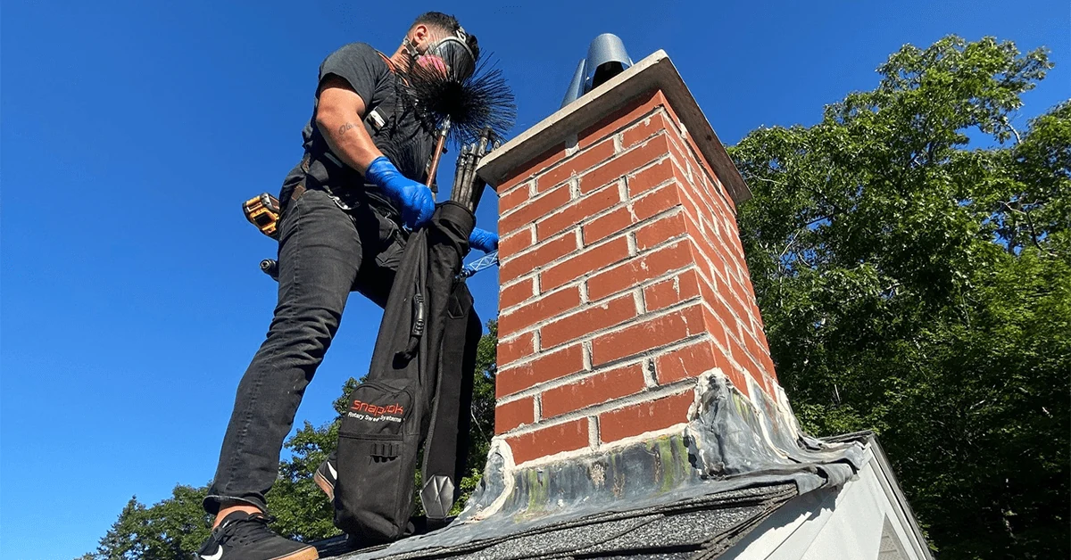 Chimney sweep professional preparing roof-level chimney cleaning equipment